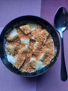 a bowl filled with food on top of a purple table cloth next to a spoon