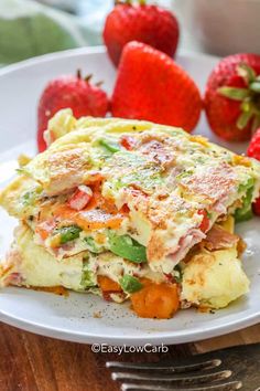 a white plate topped with an omelet next to strawberries