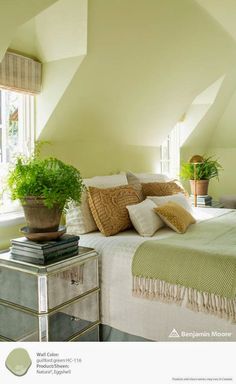 a bedroom with yellow walls and green plants in the window sill on the bed