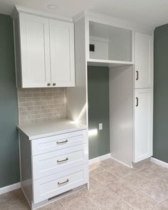 an empty kitchen with white cabinets and gray wall paint on the walls, tile flooring