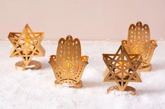 three small gold candlesticks in the shape of stars on top of snow covered ground