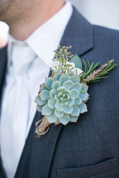 a man wearing a suit and tie with a succulent boutonniere on his lapel