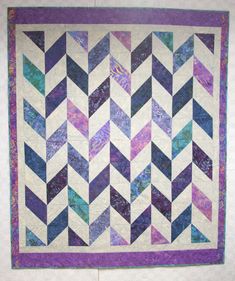 a quilted wall hanging with purple, blue and green chevrons on it