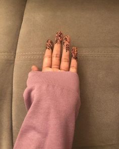 a woman's hand with leopard print on it, sitting on a couch next to her pink sweater