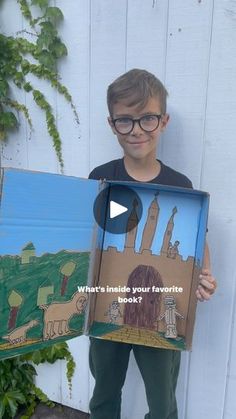 a young boy holding up a cardboard box with an image of a castle on it