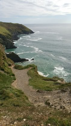 a path leading down to the ocean with cliffs in the background