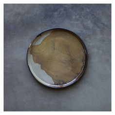 a dirty plate sitting on top of a cement floor next to a white and black wall