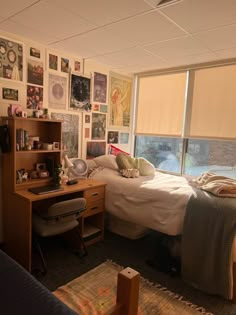 a bedroom with a bed, desk and window covered in pictures on the wall next to it