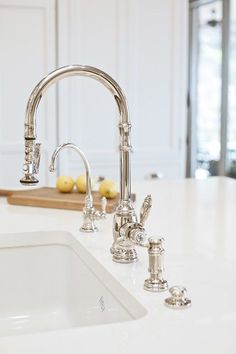 a kitchen sink with two faucets and a cutting board on the counter top