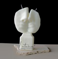 a white sculpture sitting on top of a stone slab