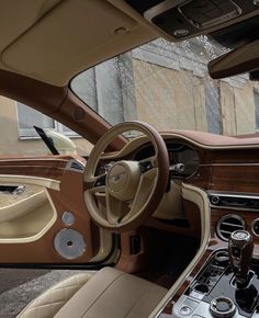 the interior of a luxury car with beige leather and wood trims, including steering wheel