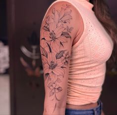 a woman's arm with flowers on it and a pink shirt in the background