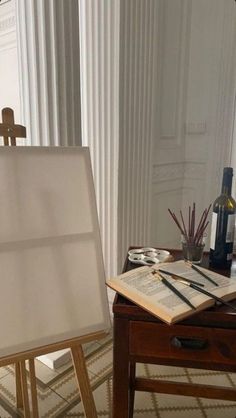 an easel is sitting on a table next to a wine bottle