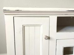 an old white cabinet with glass doors and knobs