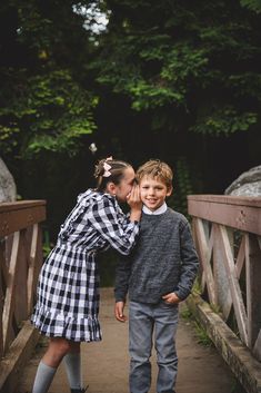 two children are standing on a bridge and touching their hands together while the other child is looking at them