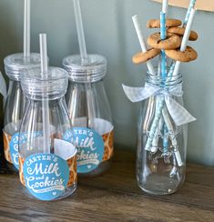 there are cookies and milk in glass jars on the table next to each other with straws sticking out of them