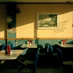 the interior of a restaurant with blue chairs and tables in front of yellow painted walls