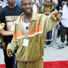 a man pointing at the camera while standing on a red carpet with people behind him