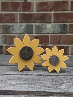 two wooden sunflowers sitting next to each other on top of a wooden table