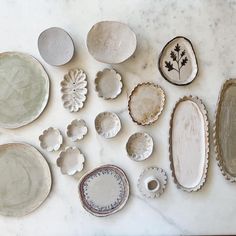 various plates and bowls are arranged on a marble table top, including one with a flower in the center