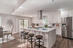 a large kitchen with white cabinets and stainless steel appliances, along with an island in the middle