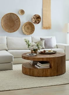 a living room with white couches and round coffee table in front of wall hangings