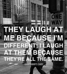 a man walking down the street next to a pole with a sign that says, they laugh at me because i'm different i laugh at them