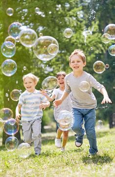 three young boys are running through soap bubbles