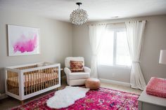 a baby's room with a pink rug and white crib