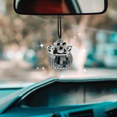 a mirror hanging from the side of a car with a disco ball ornament on it