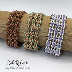 three beaded bracelets sitting on top of a wooden stick