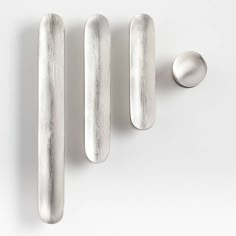 three metal objects on a white surface with one silver object in the foreground and two smaller ones behind them