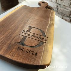 a wooden cutting board with the initials and date engraved on it