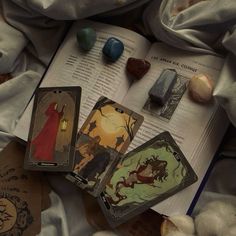 an open book with four tarot cards on top of it next to other items