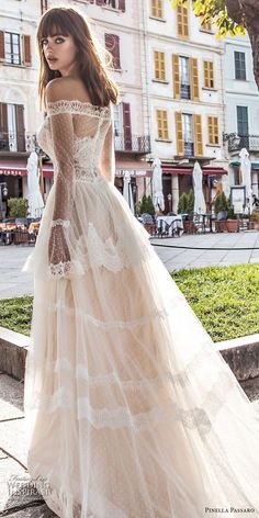 a woman in a wedding dress is standing on the sidewalk near a tree and buildings