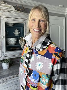 an older woman standing in front of a cabinet with flowers on it and a bird perched on her shoulder