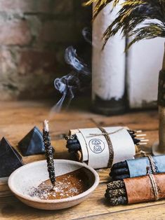 a wooden table topped with lots of different types of candles and incense sticks on top of it