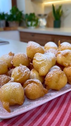 a white plate topped with donuts on top of a red and white table cloth