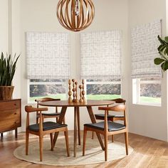 a dining room table with four chairs and a round light fixture hanging from the ceiling