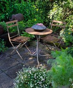 an outdoor table and chairs in a garden