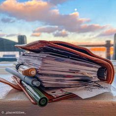 a pile of papers sitting on top of a wooden table next to a window sill