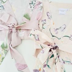 three different types of clothing tied together on a white surface with flowers and leaves around them