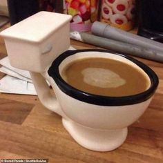 a cup of coffee sitting on top of a white toilet