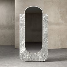 an unusual white marble mirror in the middle of a room with concrete walls and flooring