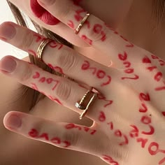 a woman with her hands covered in red paint and two gold rings on her left hand