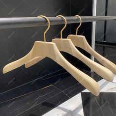 three wooden clothes hangers on a metal rail