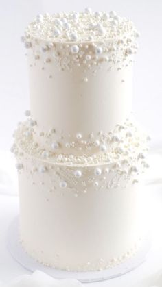 three tiered white wedding cake with pearls