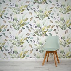 a green chair sitting in front of a wallpapered with leaves and plants on it