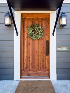 the front door is decorated with a wreath and two lights