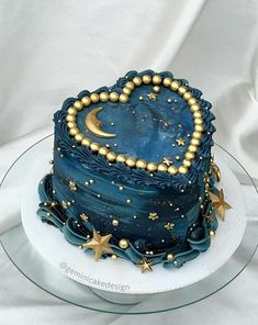 a blue cake with gold stars and a heart shaped decoration